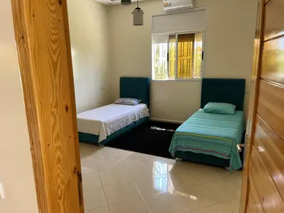 a small room with two beds and a window at Maison Dar Zarka in Aghmat