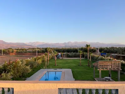 a view of a yard with a swimming pool and mountains at Maison Dar Zarka in Aghmat