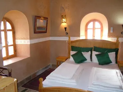 a bedroom with a bed with green and white pillows at Kasbah Hotel Ait Omar in Nkob