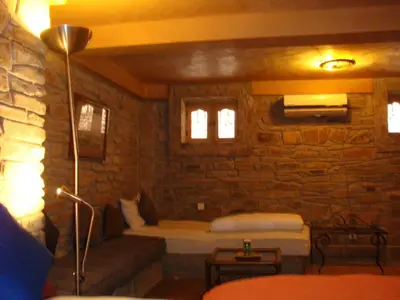 a living room with a couch and a stone wall at Kasbah Hotel Ait Omar in Nkob