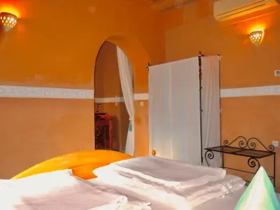 a bedroom with a bed with a mirror and a white curtain at Kasbah Hotel Ait Omar in Nkob