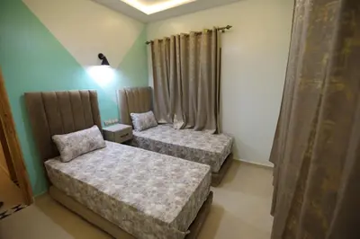 a bedroom with two beds and a lamp and curtains at مولاي يعقوب in Fès