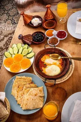 a wooden table topped with plates of food and fruit at chez aubazine in Merzouga