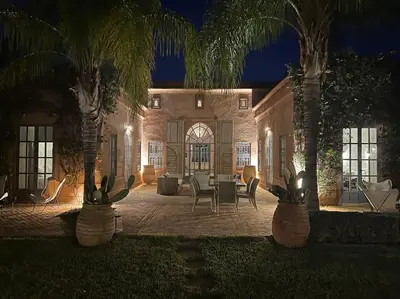 a house with two palm trees and a table and chairs at Villa-Riad Nejma in Marrakech