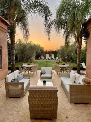 a patio with couches and tables and palm trees at Villa-Riad Nejma in Marrakech