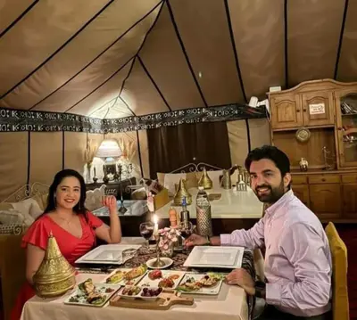 a man and woman sitting at a table with food at Merzouga Luxurious Camp in Merzouga