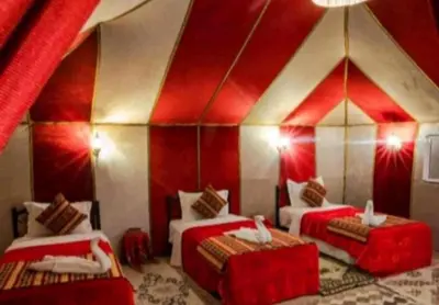 a room with two beds and a red ceiling at Merzouga Luxurious Camp in Merzouga