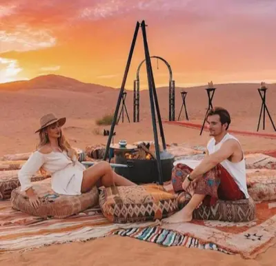 a man and a woman sitting on large tires in the desert at Merzouga Luxurious Camp in Merzouga
