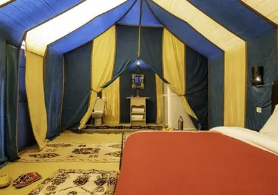 a bedroom with a blue and yellow tent at Morocco travel activities in Merzouga