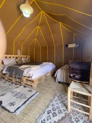 a bedroom with a tent with a bed and a chair at Morocco travel activities in Merzouga