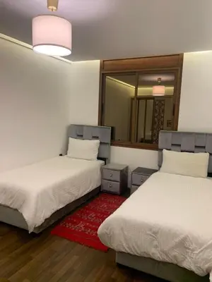 two beds in a room with a mirror and a red rug at زاوية سيدي عبد السلام افران in Ifrane