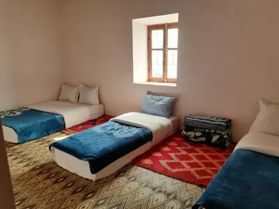 a room with three beds and a window at Gite chez Ali Agouti Maison Berbère in Agouti