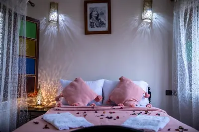 a bedroom with a bed with pink pillows and a window at Dar Elhaja Rahma in Fès