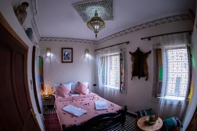 a bedroom with a bed with pink sheets and pillows at Dar Elhaja Rahma in Fès