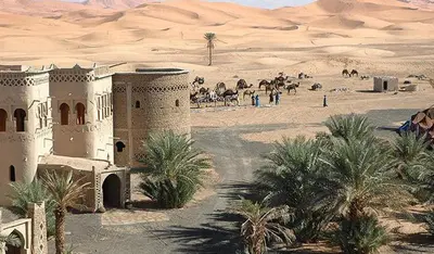 a building in the middle of a desert with people and animals at Elhachimi two bedroom with air conditioning in Er Rachidia
