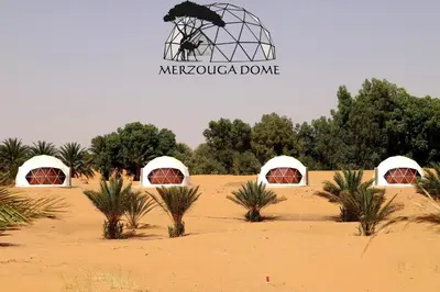a group of domes in the desert with palm trees at Merzouga Dome in Merzouga