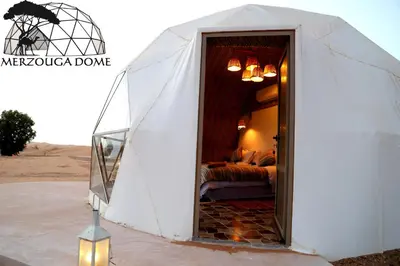a tent in the desert with a bed inside at Merzouga Dome in Merzouga