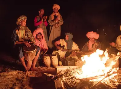 a group of people sitting around a fire at Merzouga Dome in Merzouga