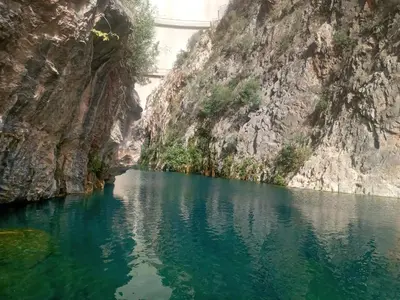 a river in a canyon with a bridge in the background at Gite Ain Bechar in Taza