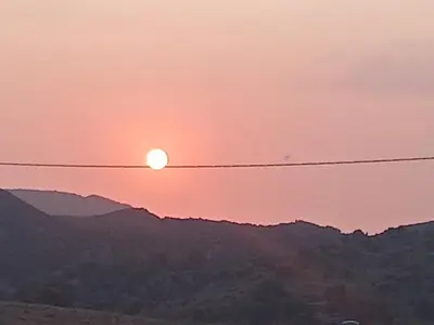 a sunset over the mountains with power lines at Gite Ain Bechar in Taza