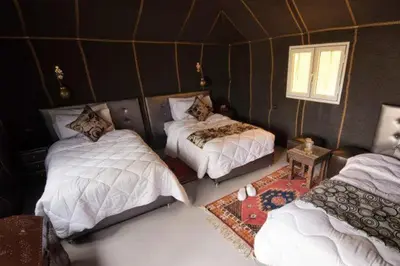 a room with two beds in a room with a wall at Hamada Activities Luxury Camp in Merzouga
