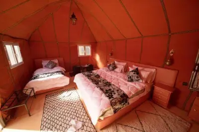 a bedroom with two beds in a room with red walls at Hamada Activities Luxury Camp in Merzouga