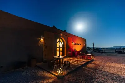 a building with a table in front of it at night at Riad Ouzina TGM in Ouzina