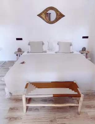 a bedroom with a large white bed and a mirror at Zagora Oasis Lodge & Desert Excursions in Zagora