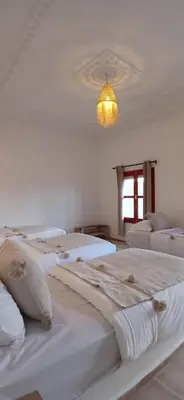 a bedroom with white beds and a chandelier at Zagora Oasis Lodge & Desert Excursions in Zagora