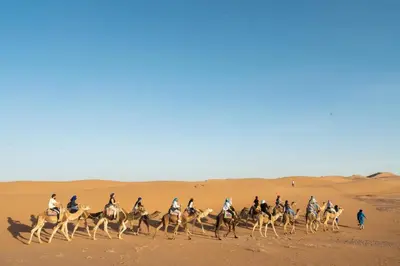 a group of people riding horses in the desert at Erg Chigaga Torza Camp - Desert Glamping in El Gouera