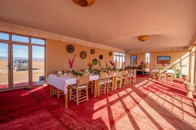 a dining room with a table and chairs and windows at Erg Chigaga Torza Camp - Desert Glamping in El Gouera