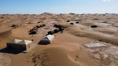 an aerial view of a desert with buildings at Erg Chigaga Torza Camp - Desert Glamping in El Gouera