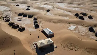 an aerial view of a desert with buildings at Erg Chigaga Torza Camp - Desert Glamping in El Gouera