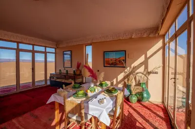 a dining room with tables and chairs and windows at Erg Chigaga Torza Camp - Desert Glamping in El Gouera