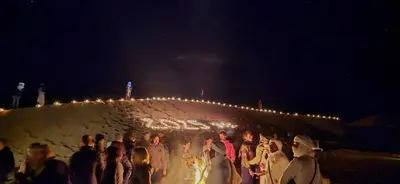 a group of people standing next to a wall with lights at Erg Chigaga Torza Camp - Desert Glamping in El Gouera