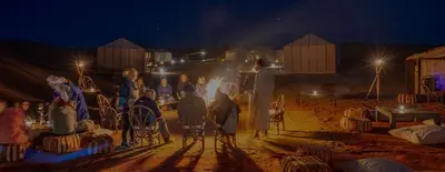 a group of people standing around a stage at night at Erg chegaga Daya Luxury Camp - Sahara Desert Stay in Mhamid
