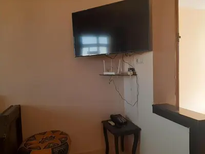 a flat screen tv hanging on a wall with a table at Charmant appartement à louer à meknès in Meknès