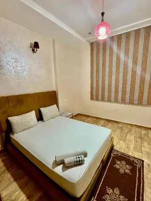 a bedroom with a bed and a pink lamp at Apprt in Fès