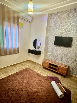 a living room with a flat screen tv and a rug at Apprt in Fès