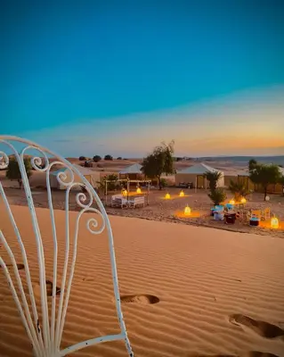 a white chair in the sand in the desert at Bohem Camp in Merzouga