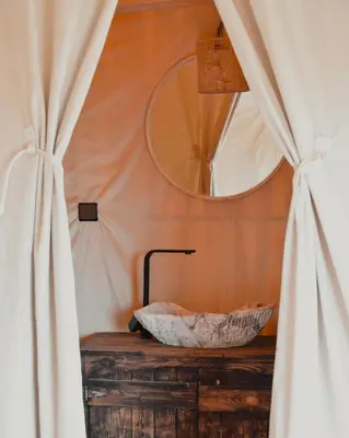 a bathroom with a sink and a mirror and curtains at Bohem Camp in Merzouga