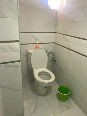 a bathroom with a toilet and a green bucket at Hotel Sotchi in Outat Oulad el Hajj
