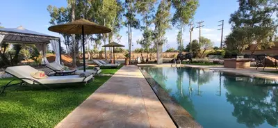 a swimming pool with two chairs and an umbrella at Le Jardin de Jeanne in Marrakech