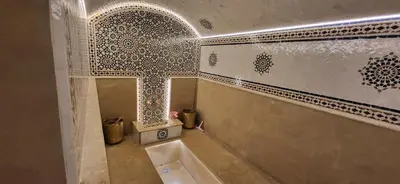 a bathroom with a tub and a tile wall at Le Jardin de Jeanne in Marrakech