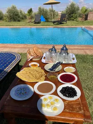 a table with food on it next to a pool at Family villa with swimming pool and a wonderful mountain view Family Only in Marrakech