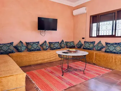 a living room with a couch with pillows and a tv at Family villa with swimming pool and a wonderful mountain view Family Only in Marrakech