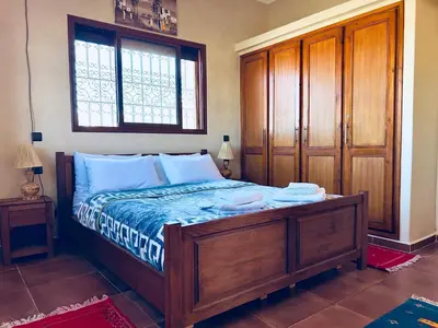 a bedroom with a bed with a wooden frame and a window at Family villa with swimming pool and a wonderful mountain view Family Only in Marrakech