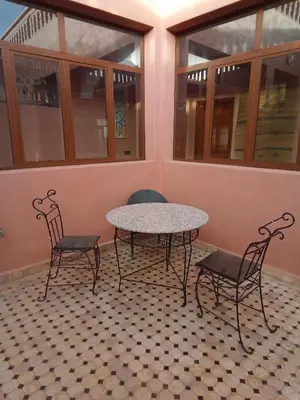 a table and chairs in a room with windows at Family villa with swimming pool and a wonderful mountain view Family Only in Marrakech