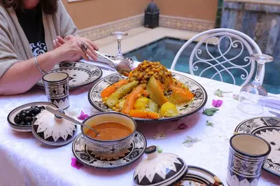 a woman sitting at a table with a plate of food at Riad Dar Susan - Authentic Stay in Zagora in Zagora