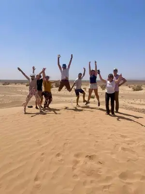 a group of people jumping in the desert at Riad Dar Susan - Authentic Stay in Zagora in Zagora